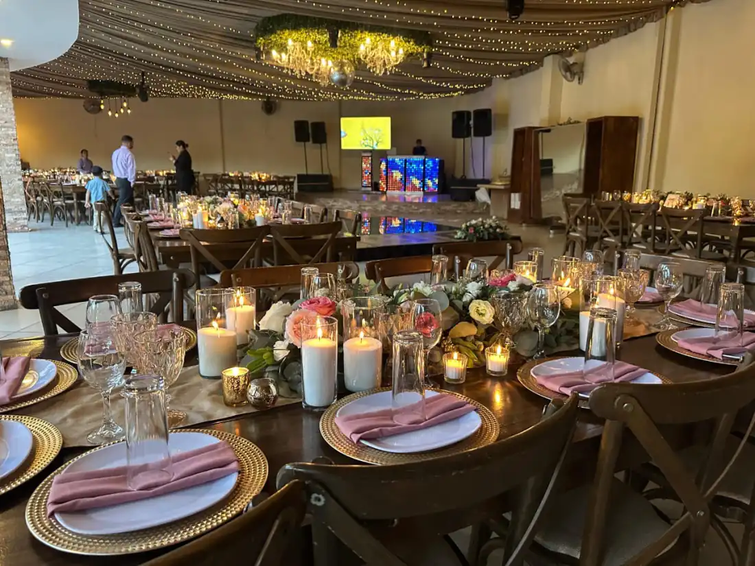 Salón techado de Bonanza montado de día, con velas, flores y servilletas rosas bajo el cielo de luces