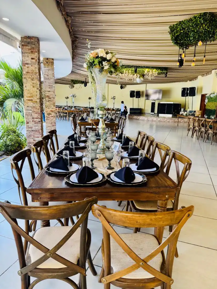 Terraza techada del salón con mesas largas de madera montadas en negro y dorado