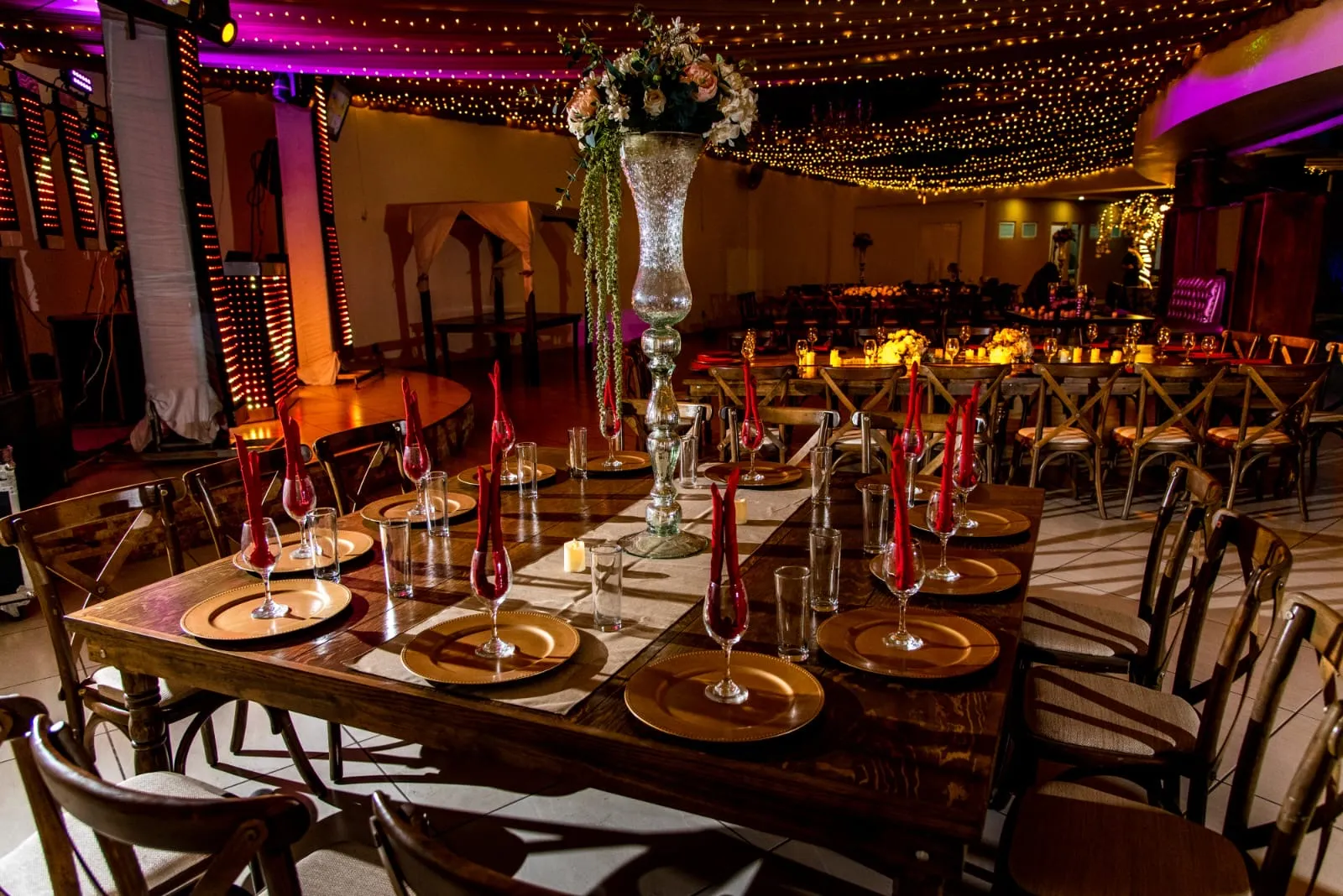 Salón de noche con cielo de luces cálidas y mesas montadas con plato base dorado